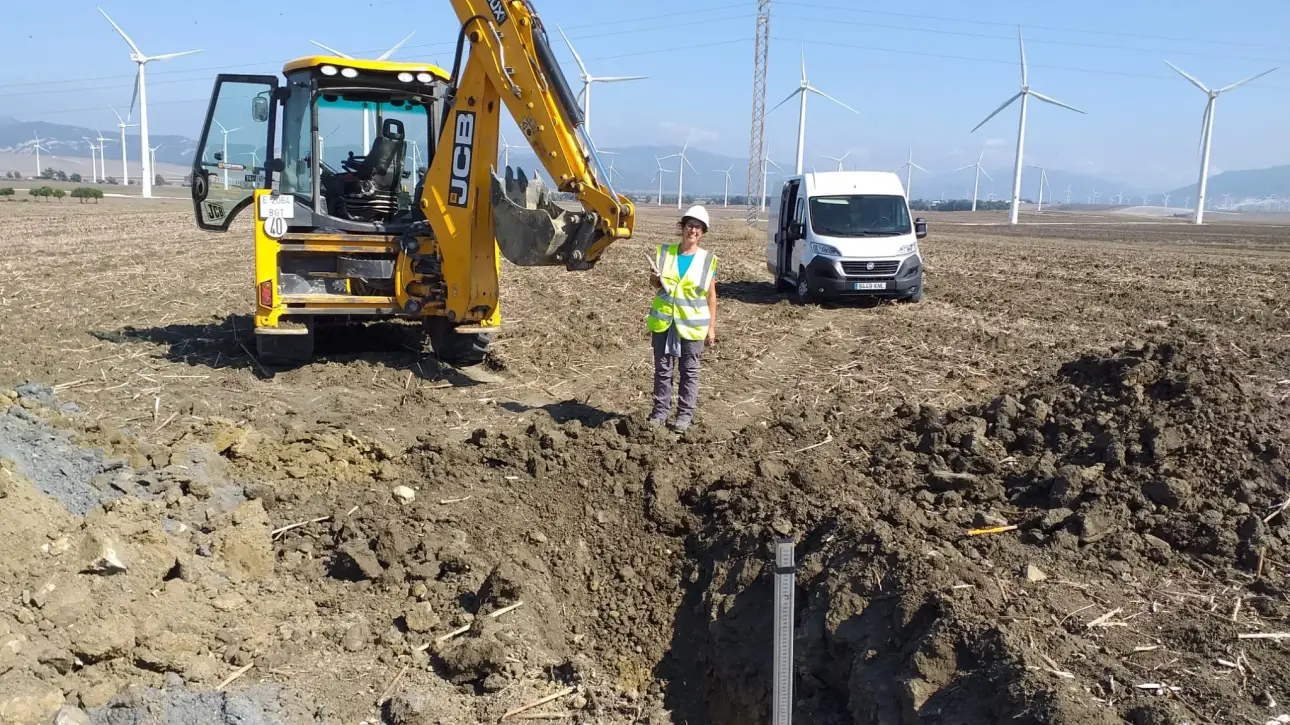 Arqueóloga supervisando un sondeo arqueológico junto a una retroexcavadora en una obra